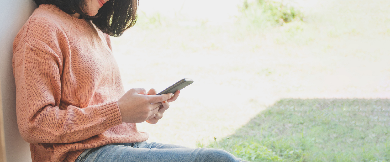 woman in sweater sitting on floor looking a phone