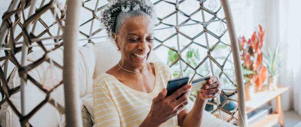 woman looking at phone holding debit card